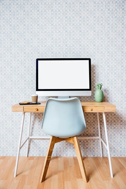 Empty chair in front of computer with blank white screen