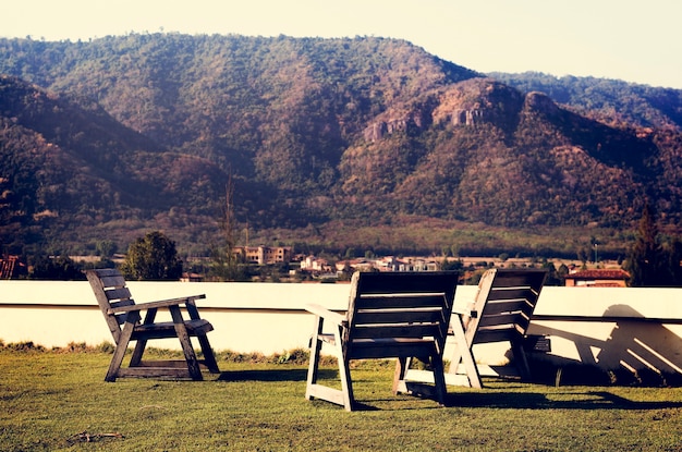 Empty Chairs on Grass Field Among Mountains Nature