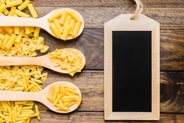 Empty chalkboard near spoons with pasta