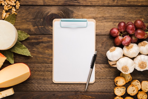 Empty clipboard and fresh ingredient on wooden desk