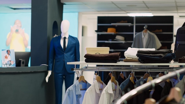 Empty clothing store with casual and formal wear design, retail shop with clothes on hangers and racks. Department store inside of shopping center, fashion merchandise on sale.