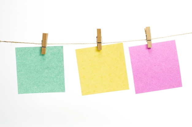 Empty colored paper sheets for notes, frames that hang on a rope with clothespins and isolated on white.