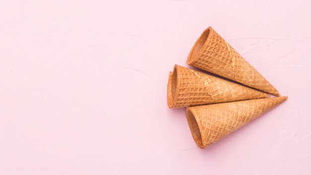 Empty crispy waffle ice cream cones on pink surface