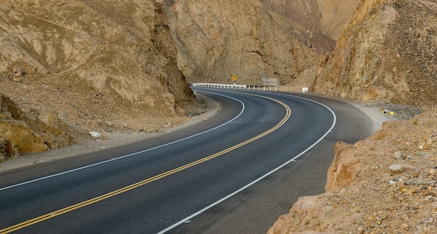 Empty curvy road in the middle of cliffs and mountains