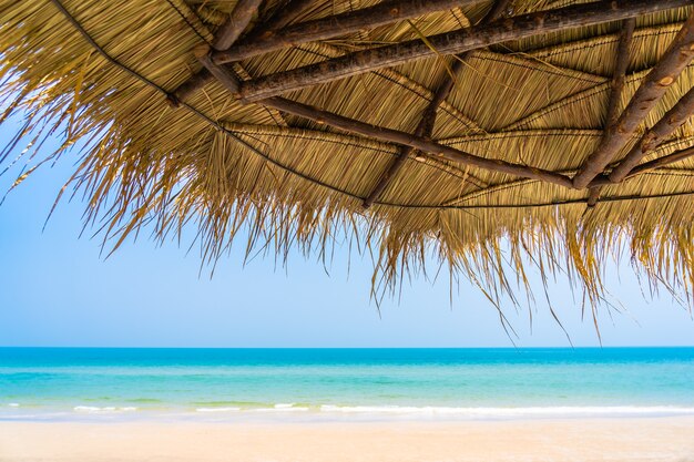 レジャー旅行の休暇のためのビーチの海の海の青い空の周りの傘と空のデッキチェアラウンジ