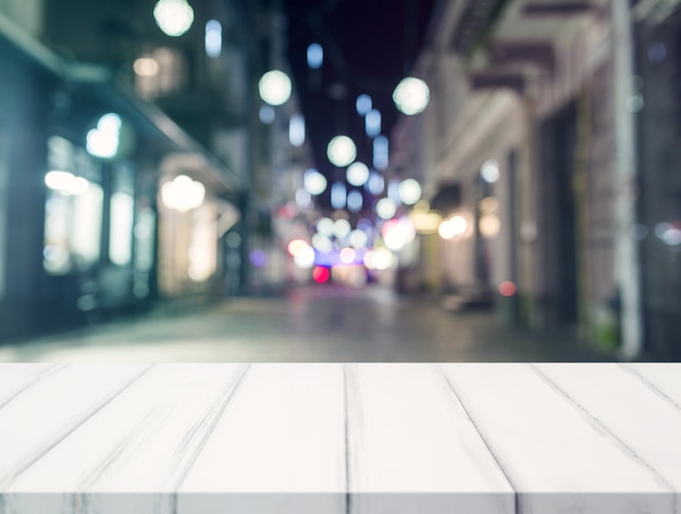 An empty desk in front of blur illuminated shopping center