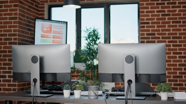 Empty desk with computers in customer service office, telecommunication and telework assistance on telephone helpline. No people in call center workplace with monitors and technology.