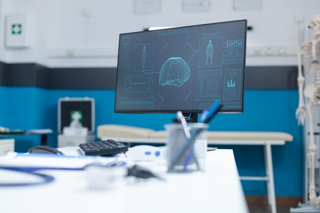 Empty doctor office with computer having anatomical body skeleton radiography on computer screen during clinical consultation. Hospital room equipped with professional medical tools. Medicine concept