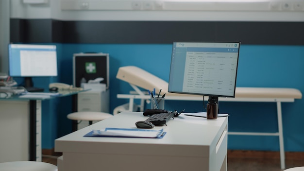 Empty doctors office with medical equipment for healthcare. Nobody in cabinet with tools, instruments, computer and checkup documents on desk. Workplace for doctor at facility.