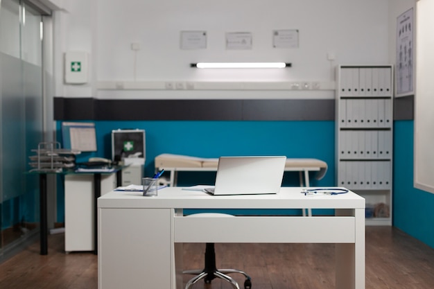 Empty doctors workplace room with desk and technology