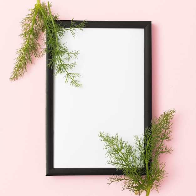 Free photo empty frame d�cor with fennel leaves on pink background