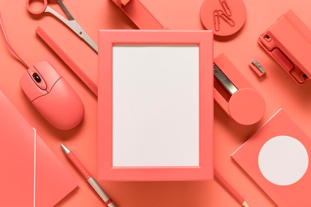 Empty frame and office supplies on colored surface
