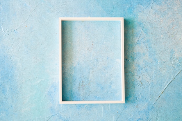 An empty frame with white border on blue painted wall