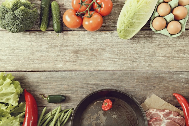 empty frying pan and vegetables, top view background