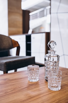 Пустая стеклянная бутылка с двумя стаканами на деревянном столе