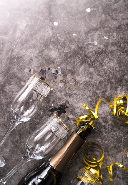 Пустая стеклянная бутылка и бутылка шампанского с декоративным элементом на бетонном фоне