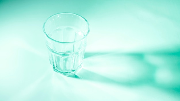 An empty glass on green colored background in sunlight