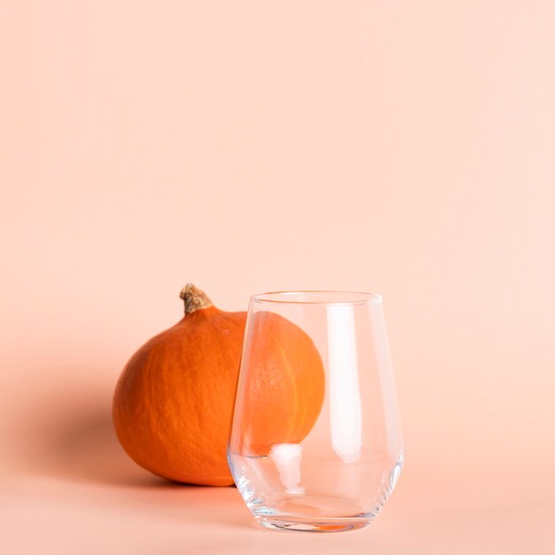 Empty glass near small pumpkin