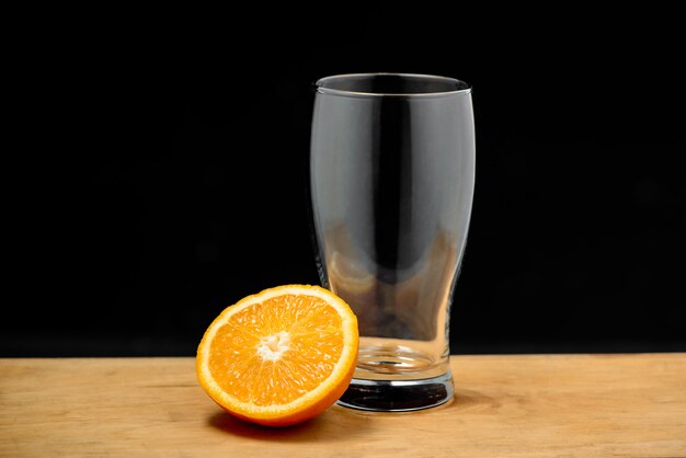 Empty glass with half orange on wooden desk