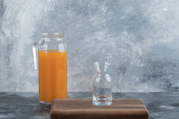 Empty glass on wooden board with jug of juice. 