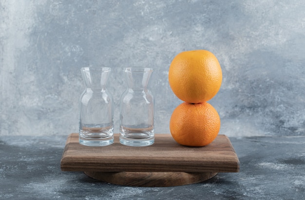 木の板に空のグラスと熟したオレンジ。