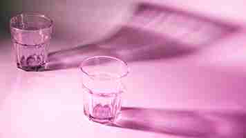 Free photo an empty glasses with dark shadow on pink background