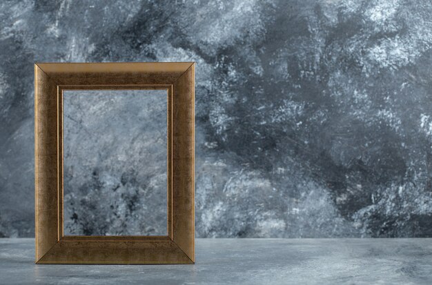 Empty golden picture frame on marble.