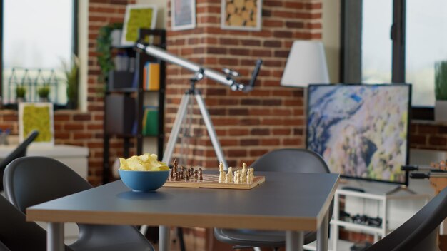 탁자 위에 체스 보드 게임과 칩이 있는 빈 내부, 친구들과 즐거운 시간을 보낼 수 있도록 준비된 공간. 여가 활동 게임으로 장식된 거실에 사람이 없고 모임을 즐깁니다.