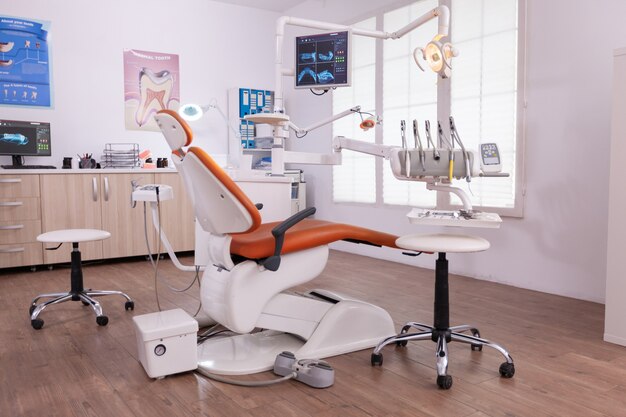 Empty modern teethcare stomatology hospital office with nobody in it equipped with dental intruments ready for orthodontist healthcare treatment. Tooth radiography images on display