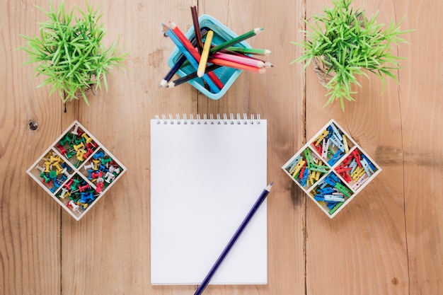 Free photo empty notebook amidst stationery and plants