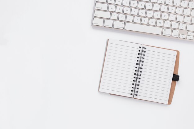 Empty notebook next to keyboard with copy space