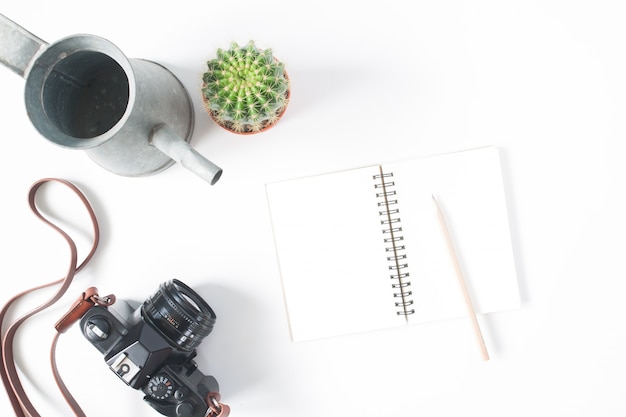 Empty notebook, pencil, film camera, pot of cactus with watering, top view, flat lay, isolated on white background