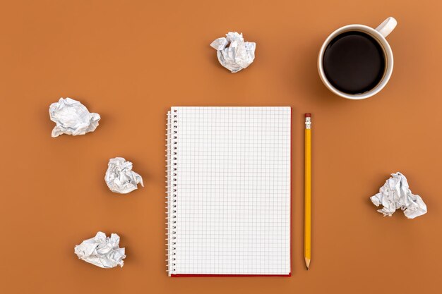 Empty notebook with cup of coffee and crumpled paper balls flat lay