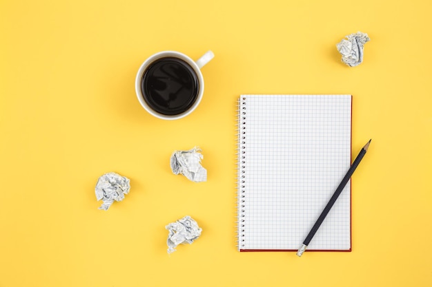 Free photo empty notebook with cup of coffee and crumpled paper balls flat lay