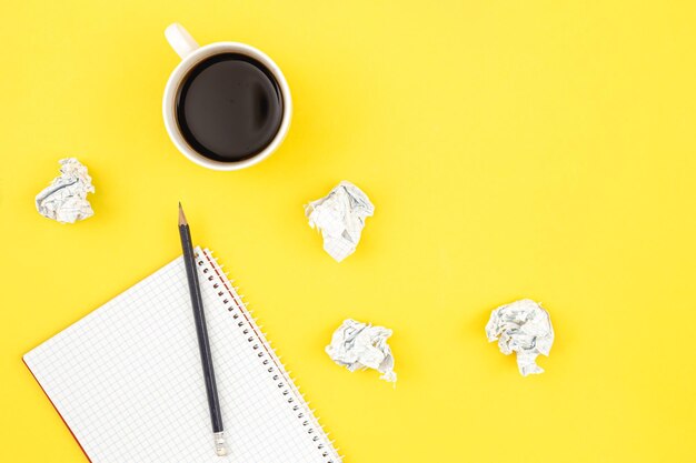 Empty notebook with cup of coffee and crumpled paper balls flat lay