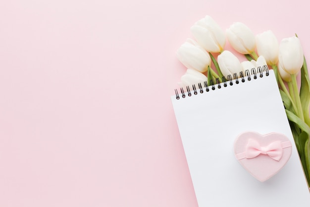 Empty notepad and gift above tulip flowers