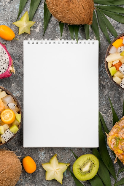 Empty notepad surrounded by exotic fruit