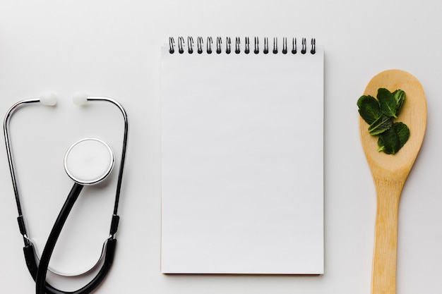 Empty notepad surrounded by stethoscope and spoon