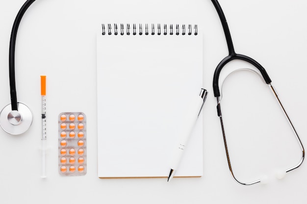 Free photo empty notepad with pills ans stethoscope