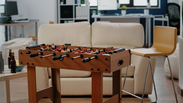 Empty office prepared for drinks and snacks after work. Nobody in workplace with foosball game table, bottles of beer and chips to do fun activity and entertainment after hours.