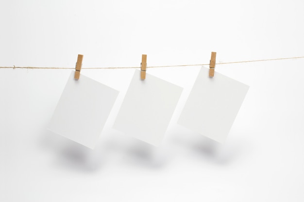 Empty paper frames that hang on a rope with clothespins and isolated on white. Blank cards on rope.