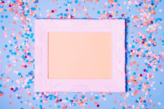 Empty photo frame and decorative confetti on blue background
