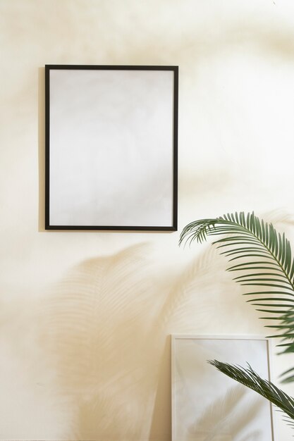 Empty photo frame on wall and plant