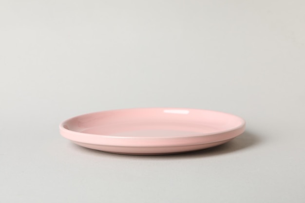 회색 배경에 빈 분홍색 접시를 닫습니다.