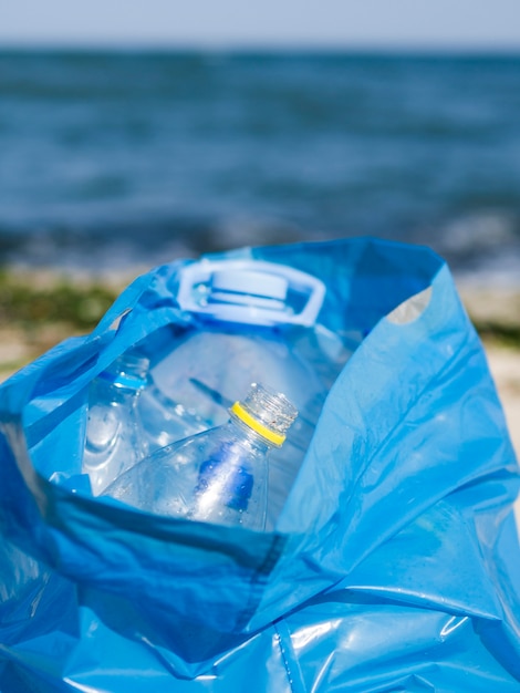 Empty plastic bottle in blue garbage bag at outdoors