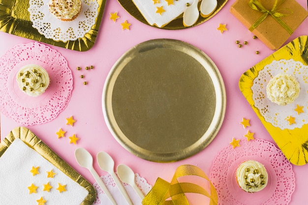 Empty plate surrounded with muffins on decorative pink background