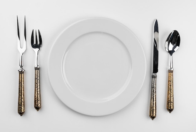 Пустая тарелка со столовыми приборами, изолированные на белом фоне