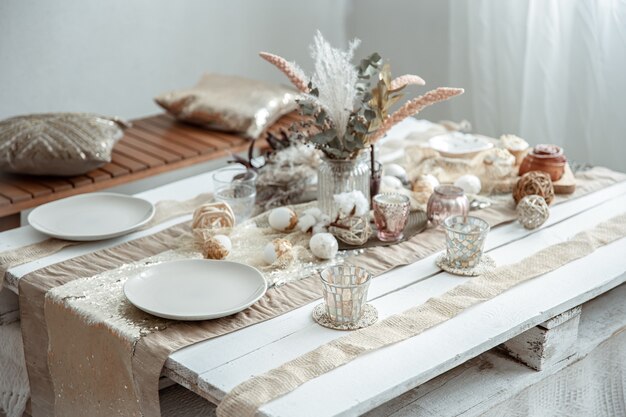 Пустые тарелки и стаканы на украшенном обеденном столе на праздник Пасхи. Красивая сервировка стола в стиле хюгге.