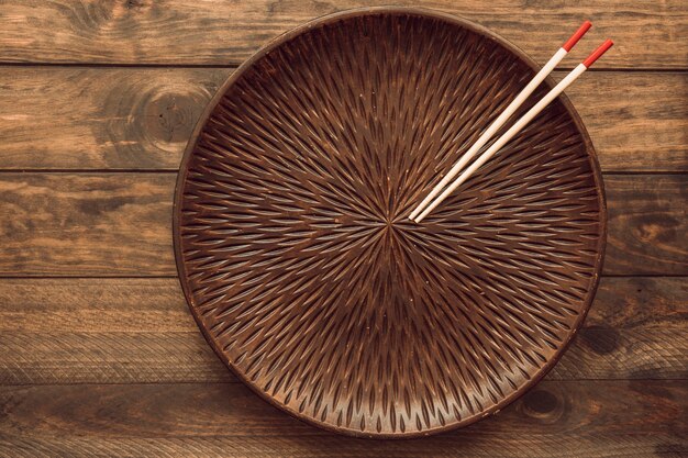 テーブルの上に2つの木製の箸を持つ空の丸いプレート