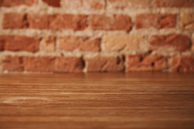 Empty rustic brown wooden table with brick wall behind, background for still life and other compositions